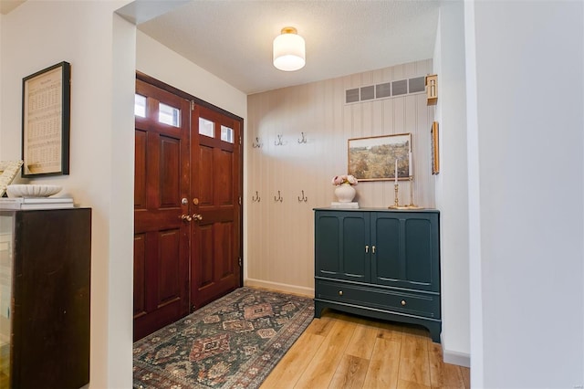 entryway with baseboards, a textured ceiling, and light wood finished floors