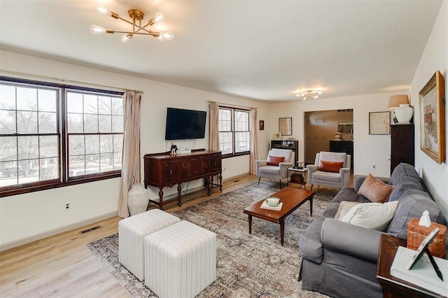 living room featuring visible vents, baseboards, wood finished floors, and a chandelier