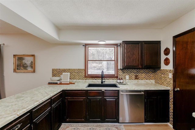 kitchen featuring backsplash, dishwasher, light countertops, a textured ceiling, and a sink