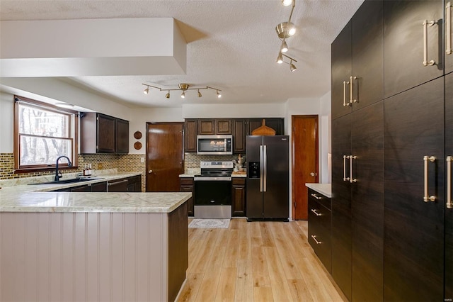 kitchen with light wood-type flooring, a sink, tasteful backsplash, stainless steel appliances, and light countertops