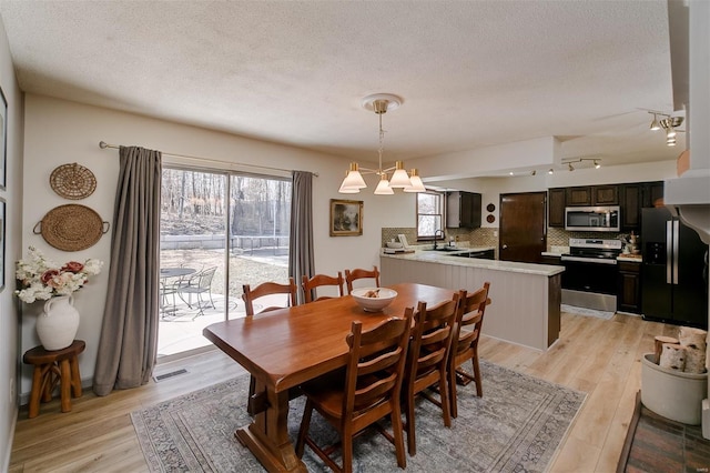 dining area with visible vents, a textured ceiling, and light wood-style flooring