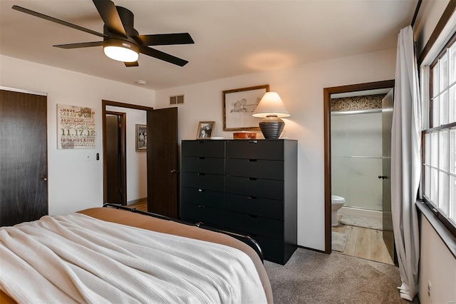 bedroom featuring light carpet, visible vents, ensuite bath, and ceiling fan