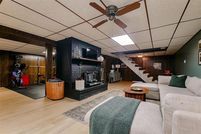 living area with stairway, wooden walls, wood finished floors, and a wood stove