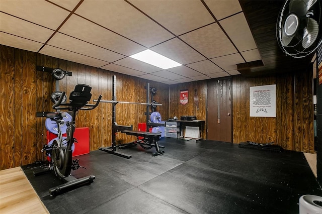 exercise room featuring a drop ceiling and wood walls