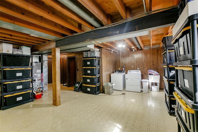 unfinished basement with tile patterned floors, washer and clothes dryer, a sink, heating unit, and wood walls