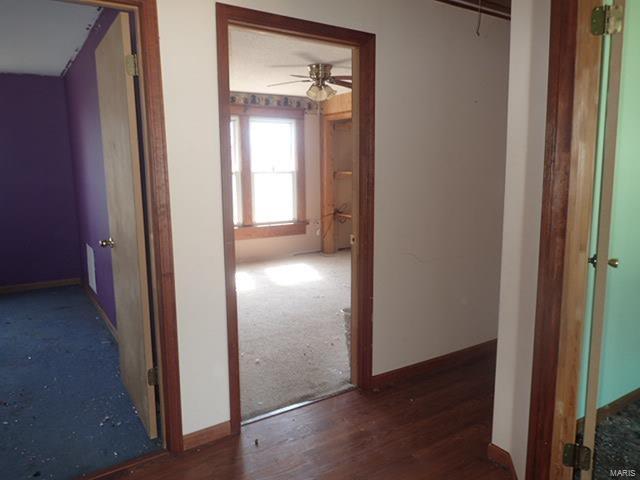 corridor featuring baseboards and wood finished floors