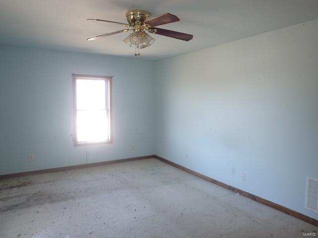 spare room featuring baseboards, visible vents, and ceiling fan