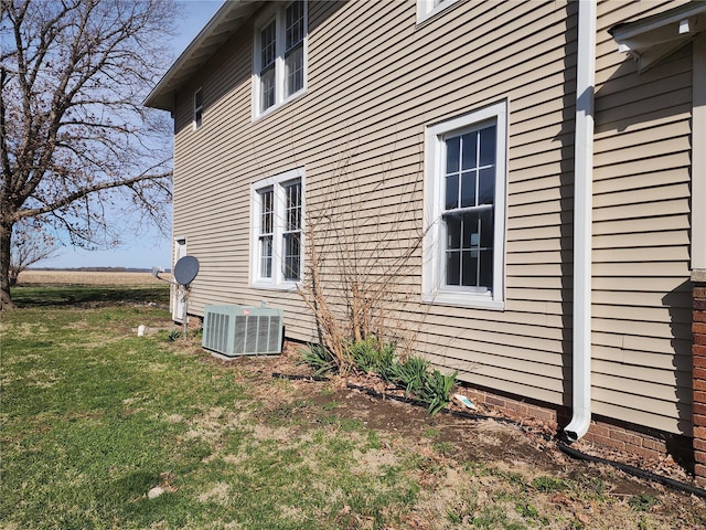 view of side of home with a lawn and central AC unit