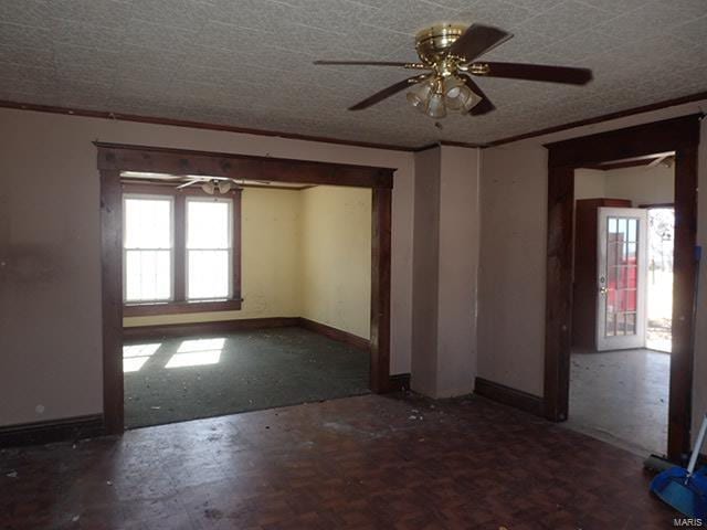 empty room with a ceiling fan, ornamental molding, baseboards, and a textured ceiling