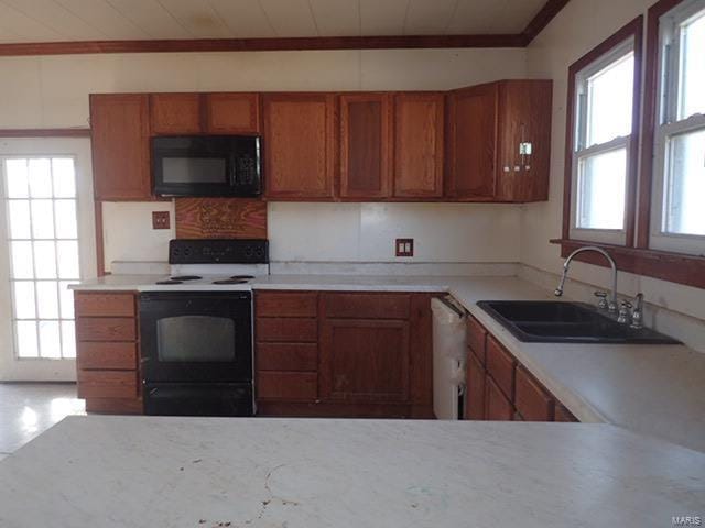 kitchen featuring dishwasher, a sink, black microwave, brown cabinetry, and electric range