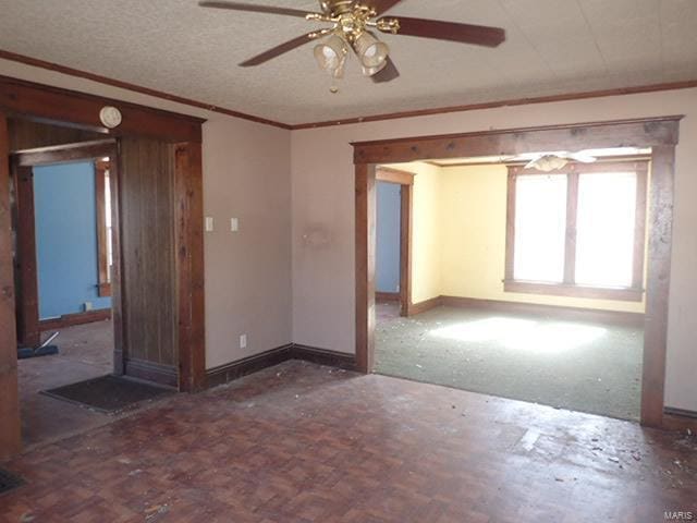 unfurnished room featuring a ceiling fan, crown molding, baseboards, and a textured ceiling