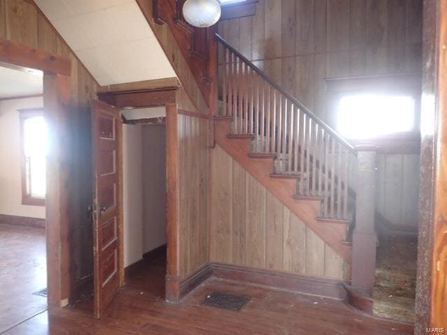 stairs featuring visible vents, wood finished floors, and wood walls