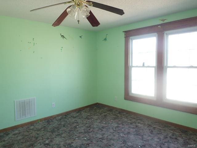 unfurnished room featuring plenty of natural light, visible vents, carpet flooring, and a textured ceiling