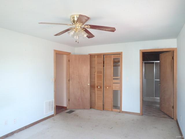unfurnished bedroom featuring a closet, visible vents, baseboards, a ceiling fan, and unfinished concrete flooring