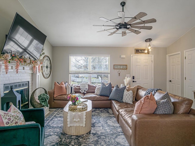 living area featuring lofted ceiling, ceiling fan, and a fireplace