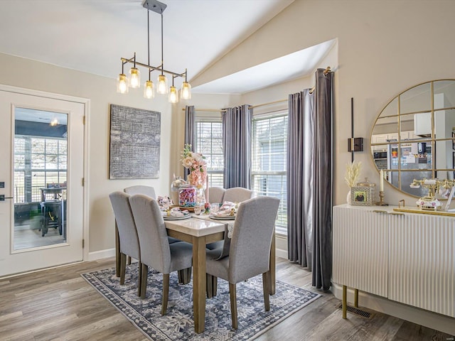 dining space featuring lofted ceiling, wood finished floors, visible vents, and baseboards