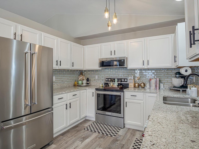 kitchen featuring backsplash, light wood-type flooring, lofted ceiling, appliances with stainless steel finishes, and a sink