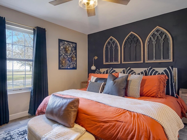 bedroom with ceiling fan, baseboards, multiple windows, and wood finished floors