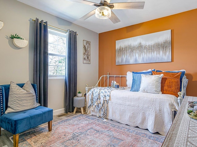 bedroom with ceiling fan, baseboards, and wood finished floors