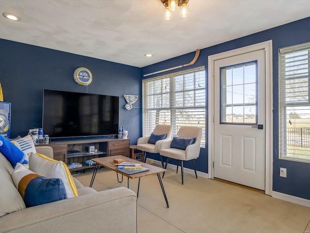 living area featuring a wealth of natural light, baseboards, and carpet floors