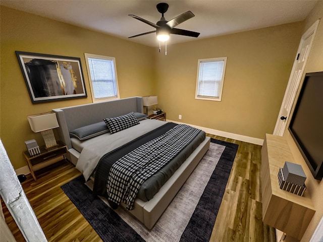 bedroom featuring ceiling fan, baseboards, and wood finished floors