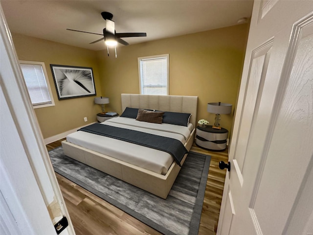 bedroom with baseboards, wood finished floors, and a ceiling fan