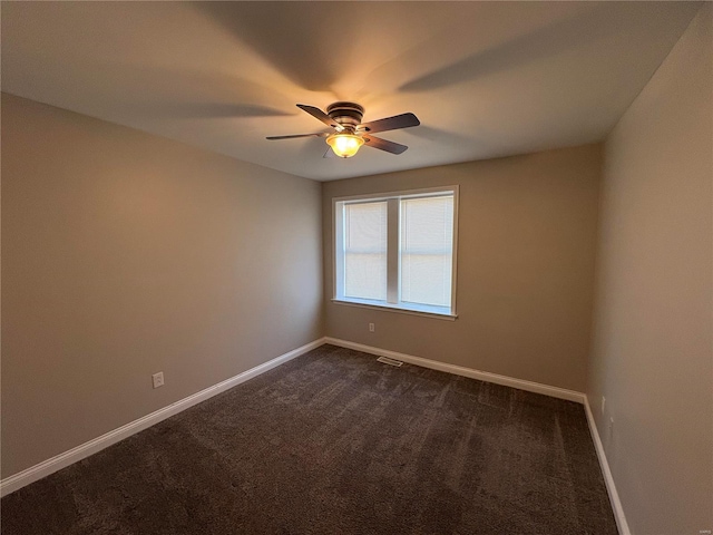 empty room featuring visible vents, baseboards, dark colored carpet, and ceiling fan