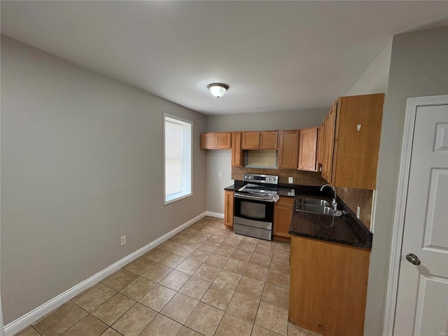 kitchen featuring dark countertops, backsplash, baseboards, electric range, and a sink