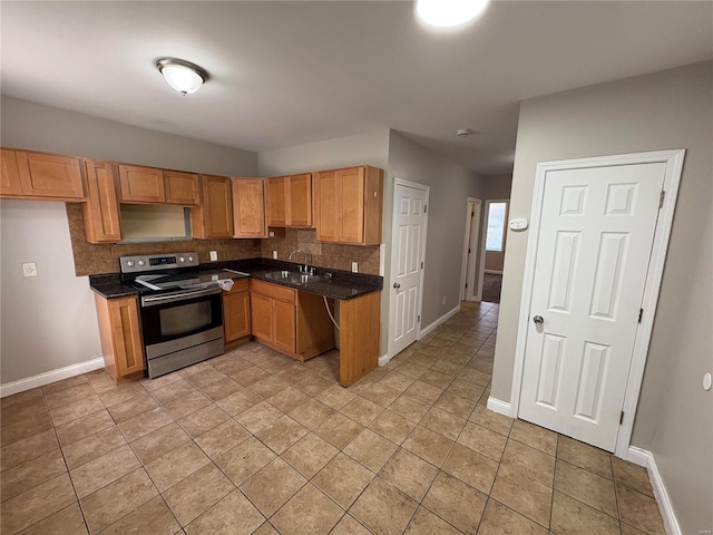 kitchen featuring dark countertops, stainless steel electric range, backsplash, and a sink