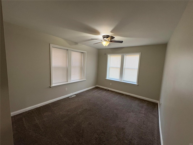 unfurnished room featuring visible vents, dark carpet, baseboards, and ceiling fan