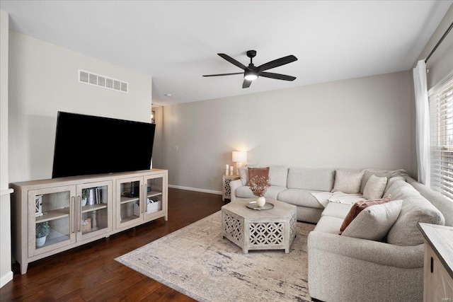 living area featuring visible vents, baseboards, a ceiling fan, and dark wood-style flooring