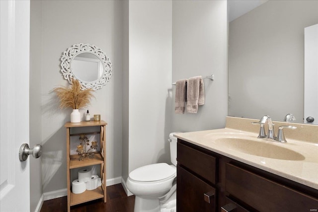 bathroom featuring baseboards, toilet, wood finished floors, and vanity