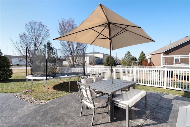 view of patio featuring outdoor dining space, a trampoline, and fence