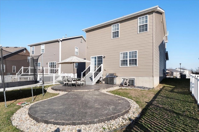 rear view of house with a patio, a trampoline, a fenced backyard, and a lawn