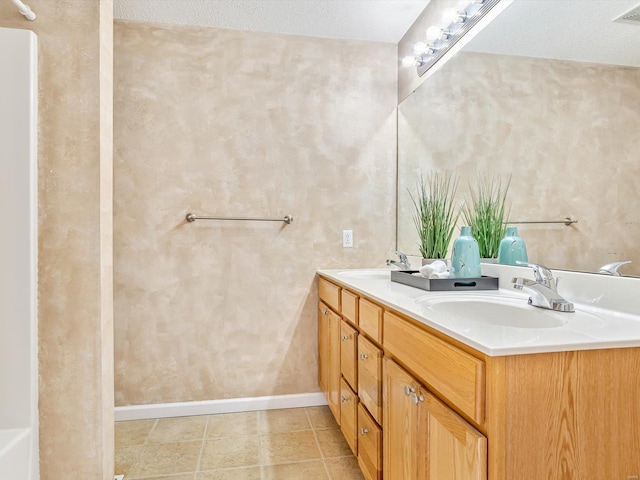 full bathroom featuring a sink, baseboards, double vanity, and tile patterned flooring