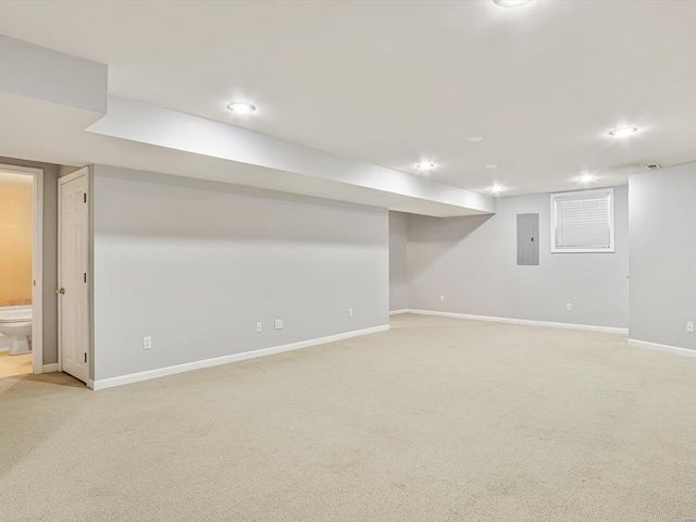 finished basement with electric panel, recessed lighting, light colored carpet, and baseboards