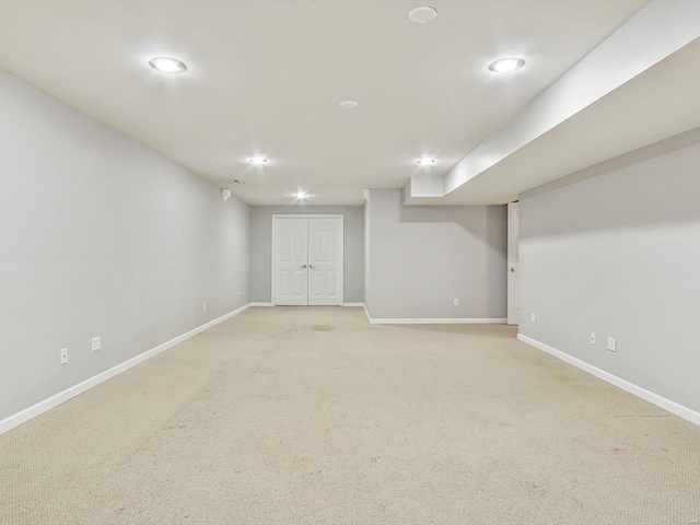 finished below grade area featuring baseboards and light colored carpet