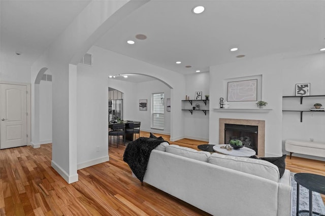 living room with visible vents, arched walkways, a fireplace, and light wood finished floors