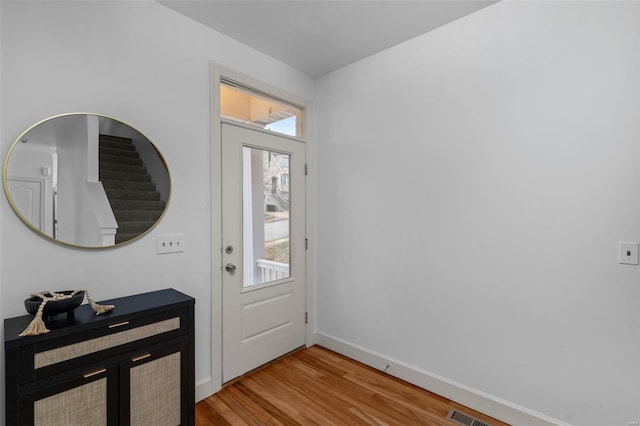 foyer with visible vents, stairs, baseboards, and wood finished floors