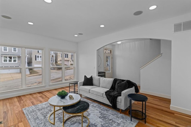 living area with visible vents, recessed lighting, wood finished floors, and arched walkways