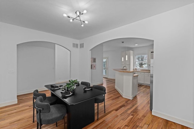 dining space featuring visible vents, light wood-style flooring, and baseboards