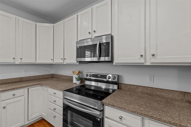 kitchen with wood finished floors, appliances with stainless steel finishes, and white cabinets