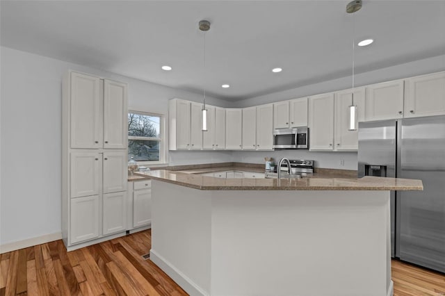 kitchen featuring white cabinetry, stainless steel appliances, light wood-style floors, and a sink