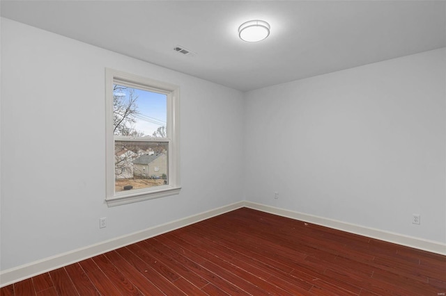 unfurnished room featuring visible vents, baseboards, and dark wood-style floors