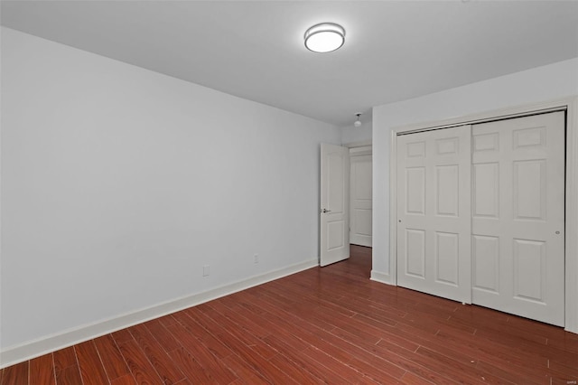 unfurnished bedroom with a closet, baseboards, and wood finished floors