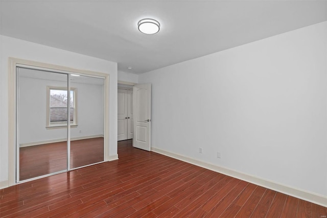 unfurnished bedroom featuring wood finished floors, a closet, and baseboards