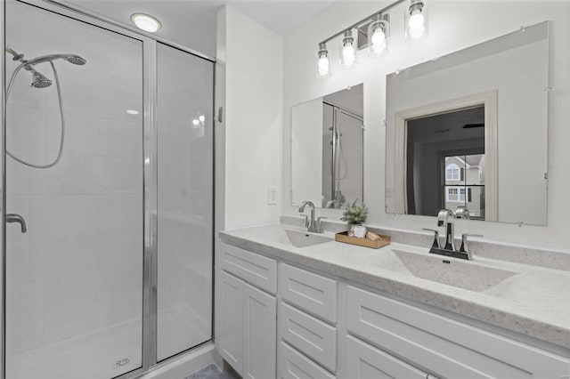 bathroom featuring double vanity, a stall shower, and a sink