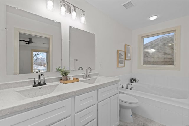 bathroom with visible vents, double vanity, a sink, a garden tub, and toilet