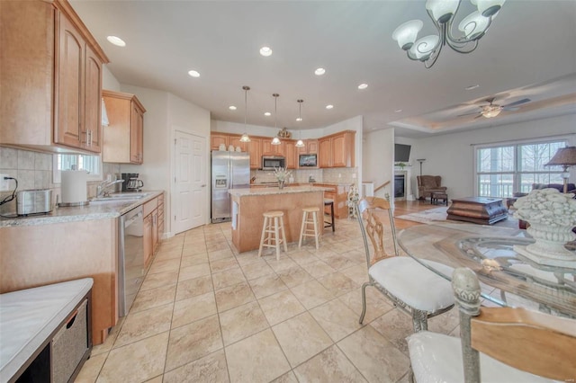 kitchen featuring a center island with sink, a kitchen bar, light countertops, appliances with stainless steel finishes, and a sink