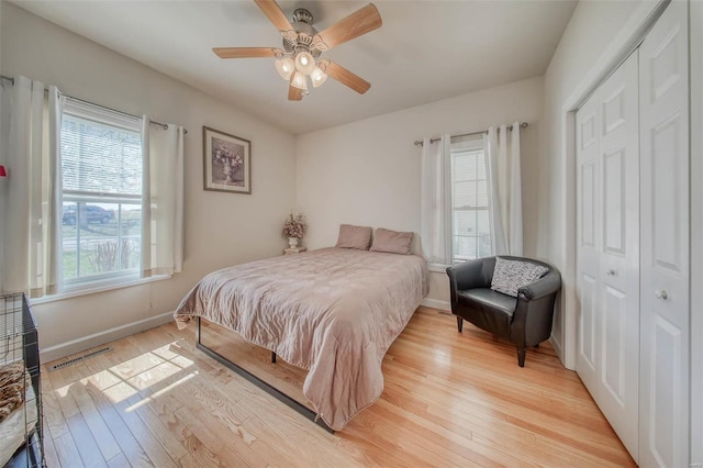 bedroom featuring visible vents, baseboards, ceiling fan, light wood-style floors, and a closet